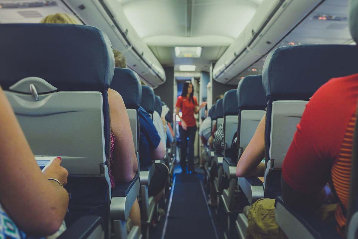 car seat flight attendant standing between passenger seat plane